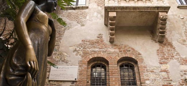 Juliet Capulet's balcony in Verona, Italy and statue Low angle shot of statue of Juliet, with balcony in the background.